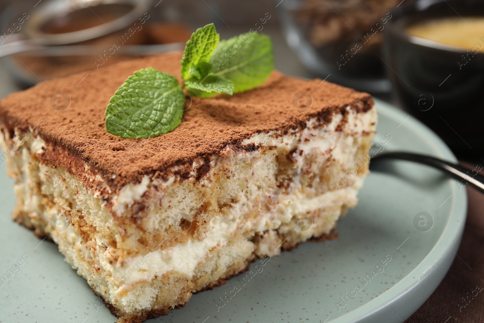 Photo of Piece of tasty tiramisu with fresh mint on table, closeup