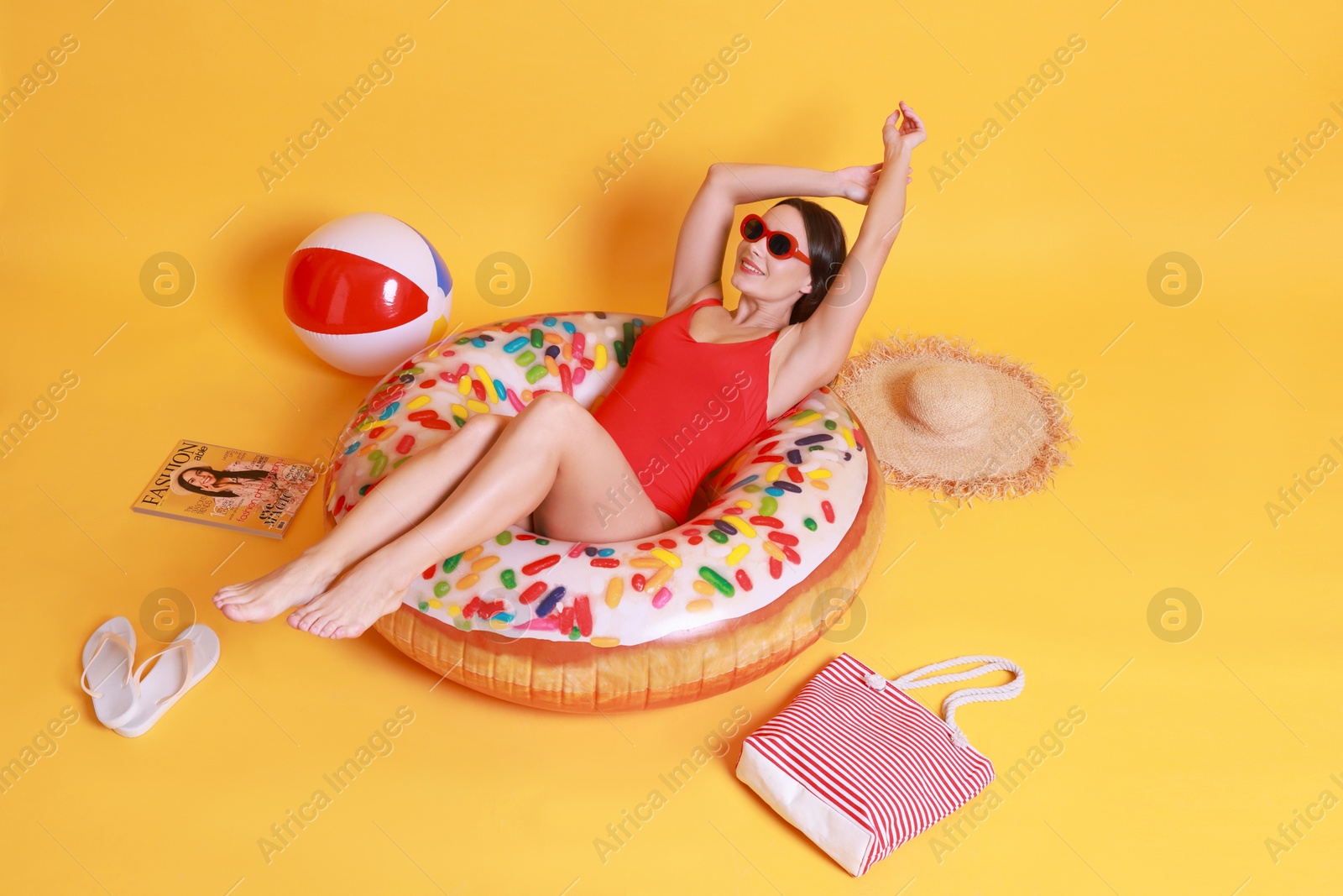 Photo of Beautiful woman in swimsuit with beach accessories on yellow background