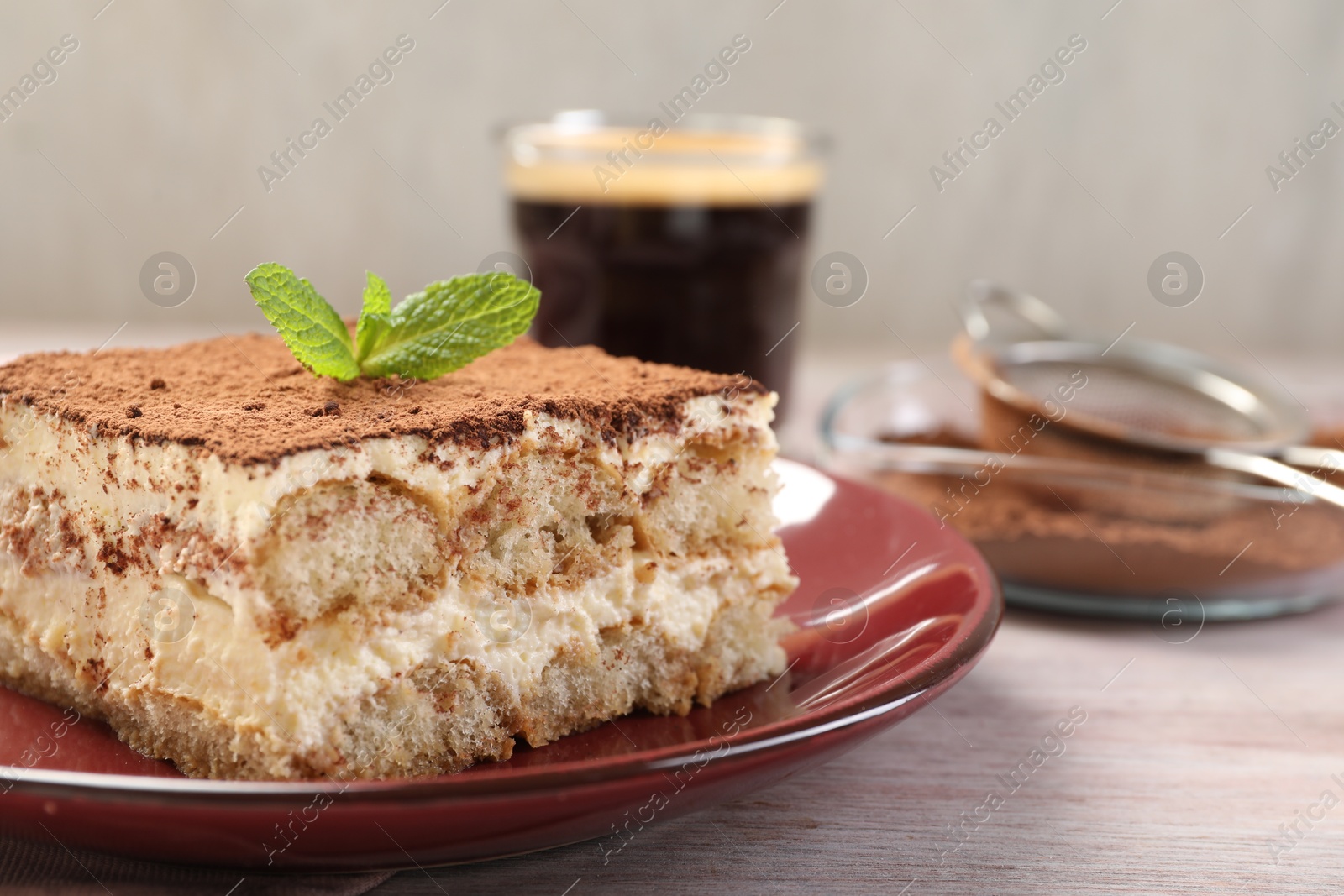 Photo of Delicious tiramisu with mint on light wooden table, closeup