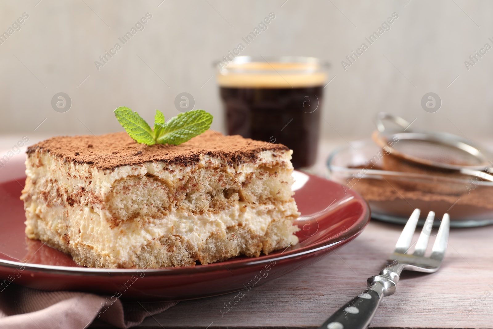 Photo of Delicious tiramisu with mint on light wooden table, closeup