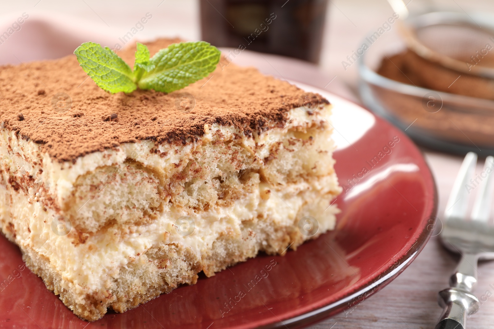 Photo of Delicious tiramisu with mint on light wooden table, closeup