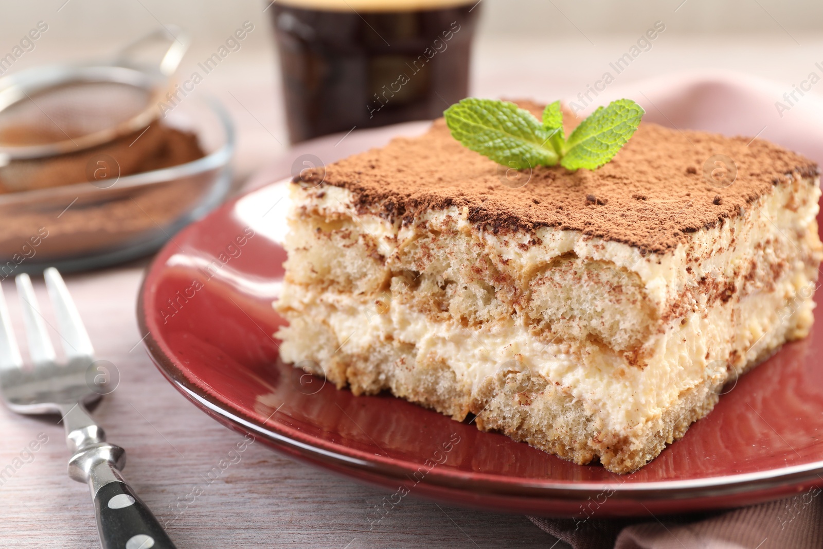 Photo of Delicious tiramisu with mint on light wooden table, closeup