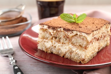 Photo of Delicious tiramisu with mint on light wooden table, closeup