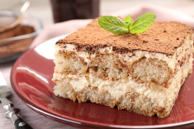 Photo of Delicious tiramisu with mint on light wooden table, closeup