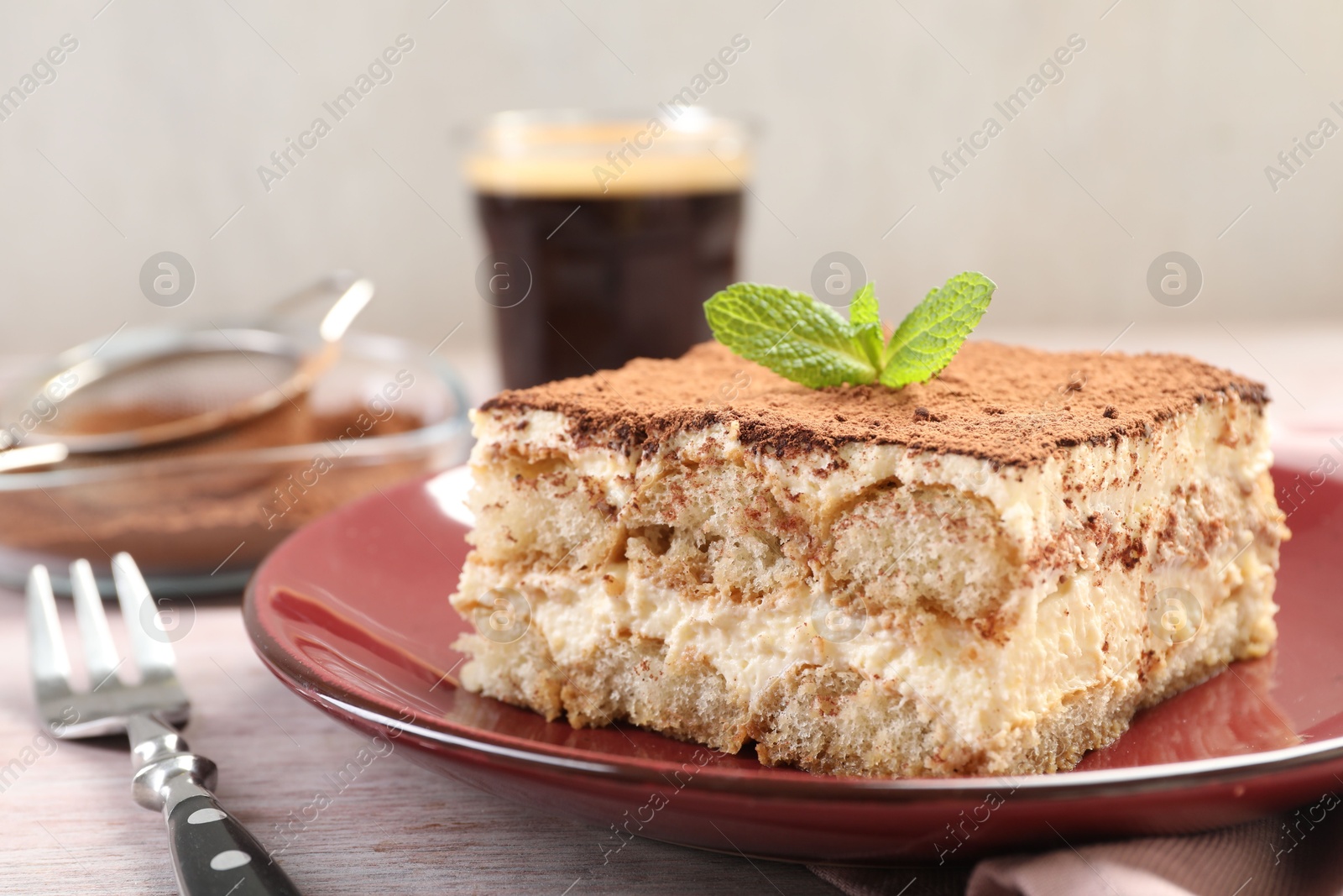 Photo of Delicious tiramisu with mint on light wooden table, closeup