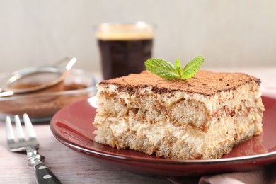 Photo of Delicious tiramisu with mint on light wooden table, closeup