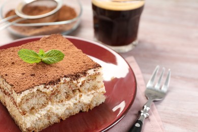 Photo of Delicious tiramisu with mint on light wooden table, closeup