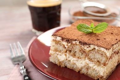 Photo of Delicious tiramisu with mint on light wooden table, closeup