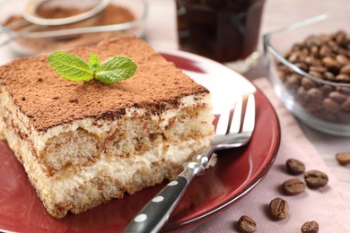 Photo of Plate with delicious tiramisu, mint and coffee beans on wooden table, closeup