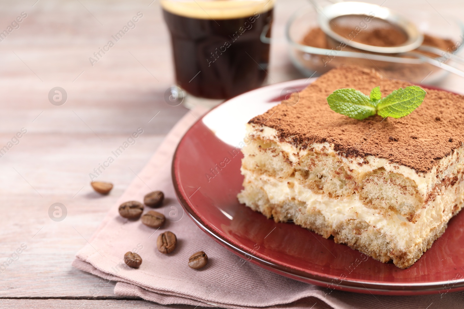 Photo of Plate with delicious tiramisu, mint and coffee beans on wooden table, closeup