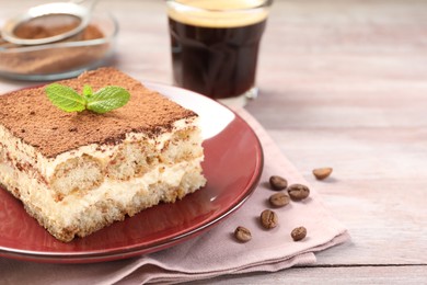 Photo of Plate with delicious tiramisu, mint and coffee beans on wooden table, closeup