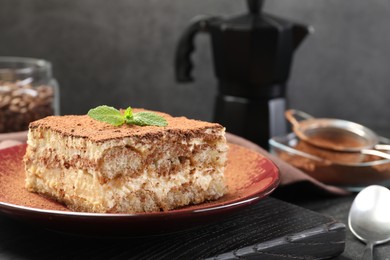 Photo of Delicious tiramisu with mint on table, closeup