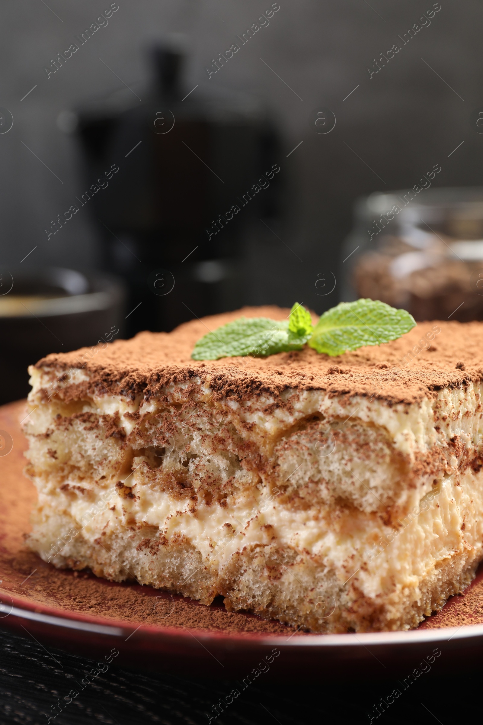 Photo of Delicious tiramisu with mint on black wooden board, closeup