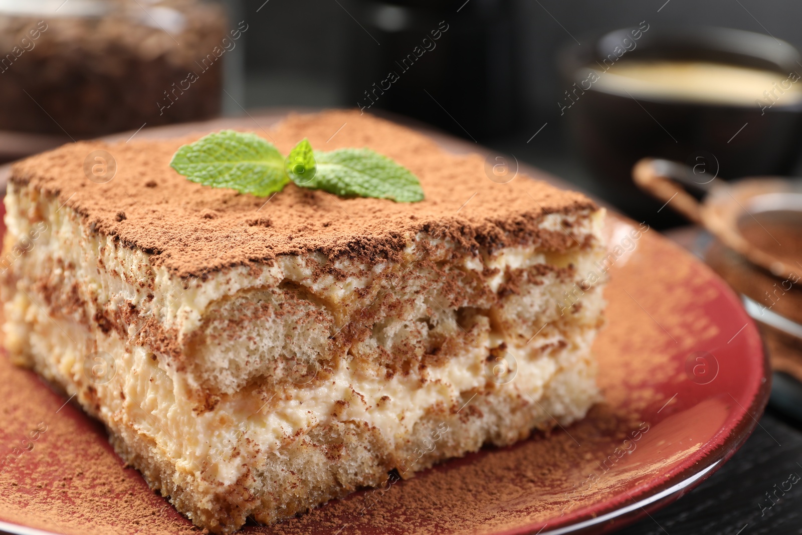 Photo of Delicious tiramisu with mint on black wooden board, closeup