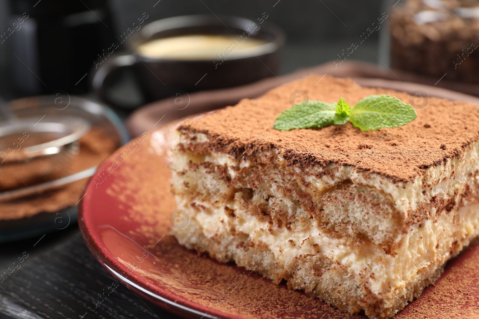 Photo of Delicious tiramisu with mint on black wooden board, closeup