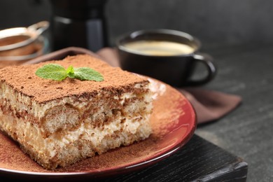 Photo of Delicious tiramisu with mint on dark table, closeup