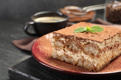 Photo of Delicious tiramisu with mint on dark table, closeup