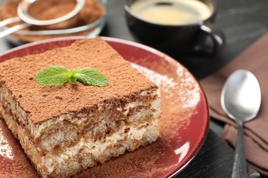 Photo of Delicious tiramisu with mint on dark table, closeup