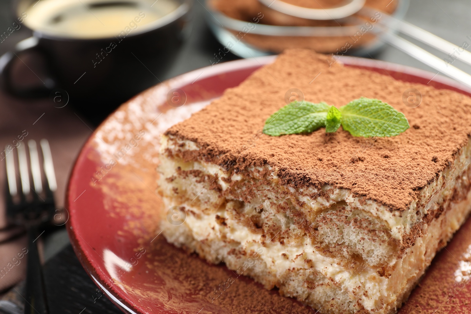 Photo of Delicious tiramisu with mint on dark table, closeup