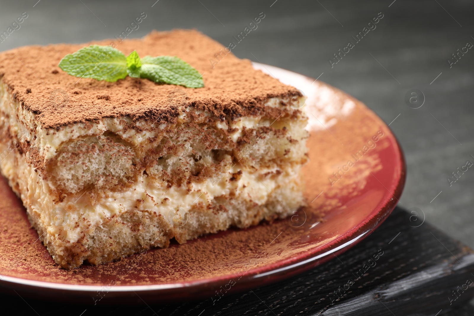 Photo of Delicious tiramisu with mint on dark table, closeup