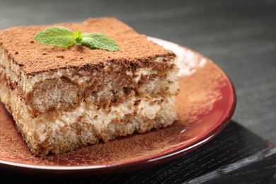 Photo of Delicious tiramisu with mint on dark table, closeup