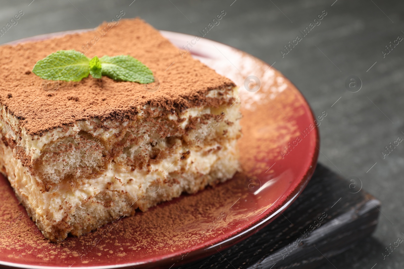 Photo of Delicious tiramisu with mint on dark table, closeup