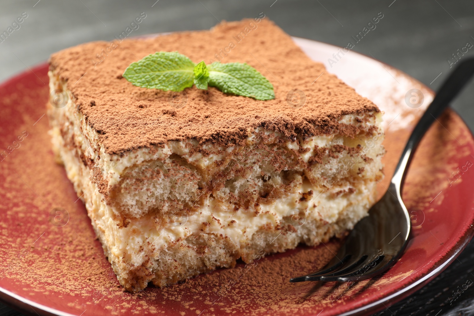 Photo of Delicious tiramisu with mint on dark table, closeup