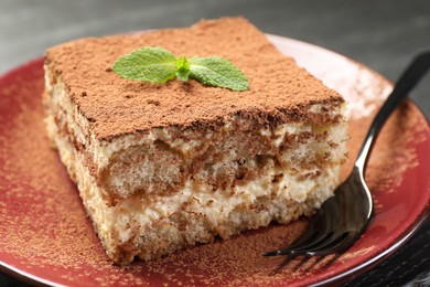 Photo of Delicious tiramisu with mint on dark table, closeup