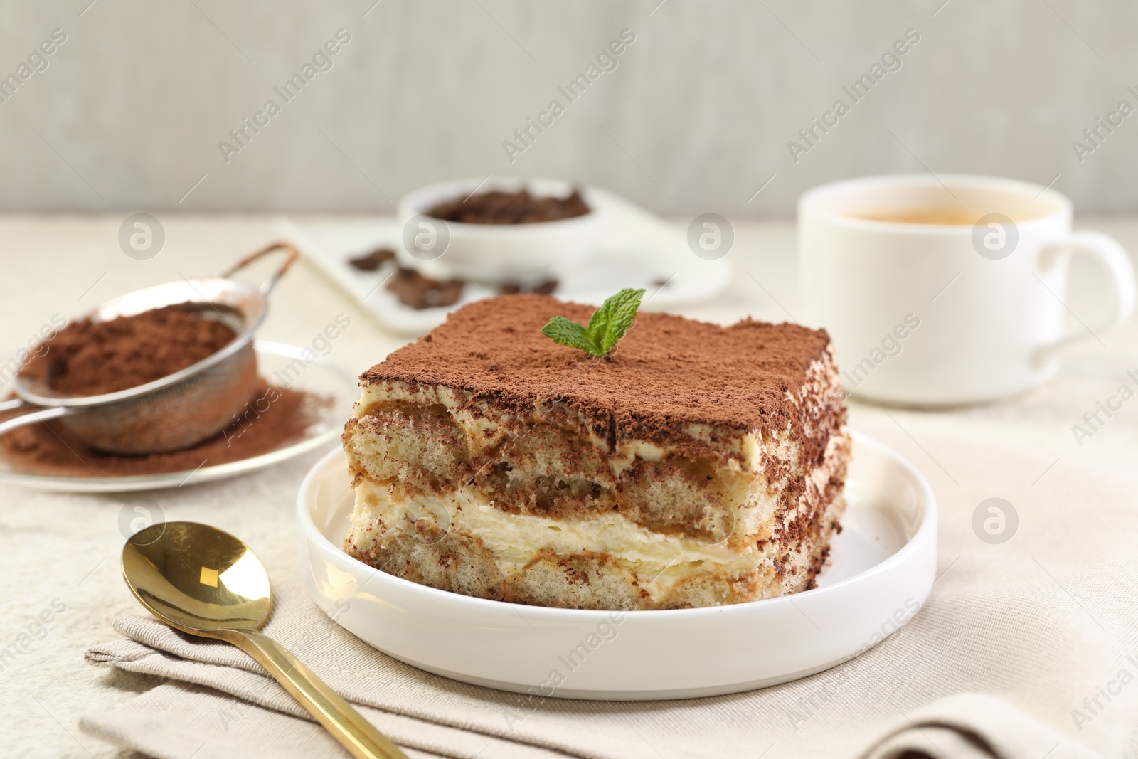 Photo of Delicious tiramisu with mint on light table, closeup