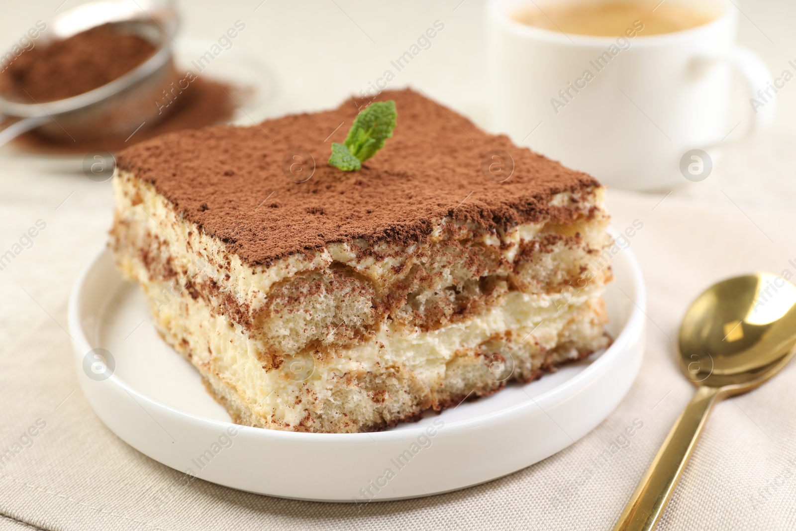 Photo of Delicious tiramisu with mint on light table, closeup