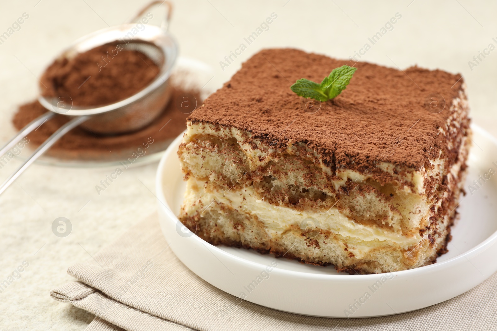 Photo of Delicious tiramisu with mint on light table, closeup