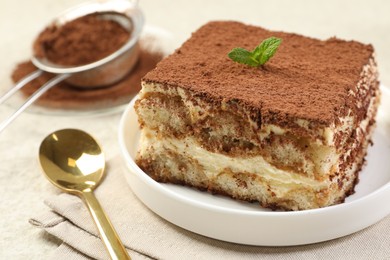 Photo of Delicious tiramisu with mint on light table, closeup