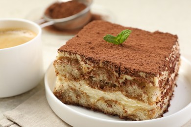 Photo of Delicious tiramisu with mint on light table, closeup