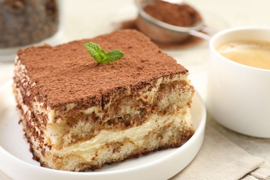 Photo of Delicious tiramisu with mint on light table, closeup