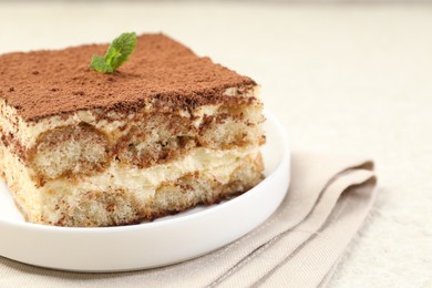 Photo of Delicious tiramisu with mint on light table, closeup