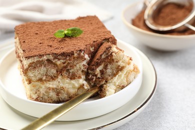 Photo of Delicious tiramisu with mint on light table, closeup