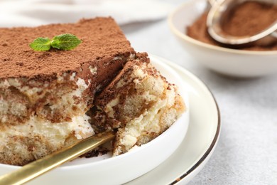 Photo of Delicious tiramisu with mint on light table, closeup