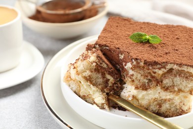 Photo of Delicious tiramisu with mint on light table, closeup