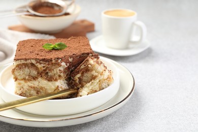 Photo of Delicious tiramisu with mint on light table, closeup. Space for text