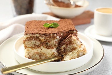 Photo of Delicious tiramisu with mint on light table, closeup