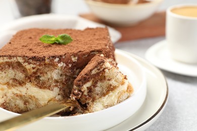 Photo of Delicious tiramisu with mint on light table, closeup