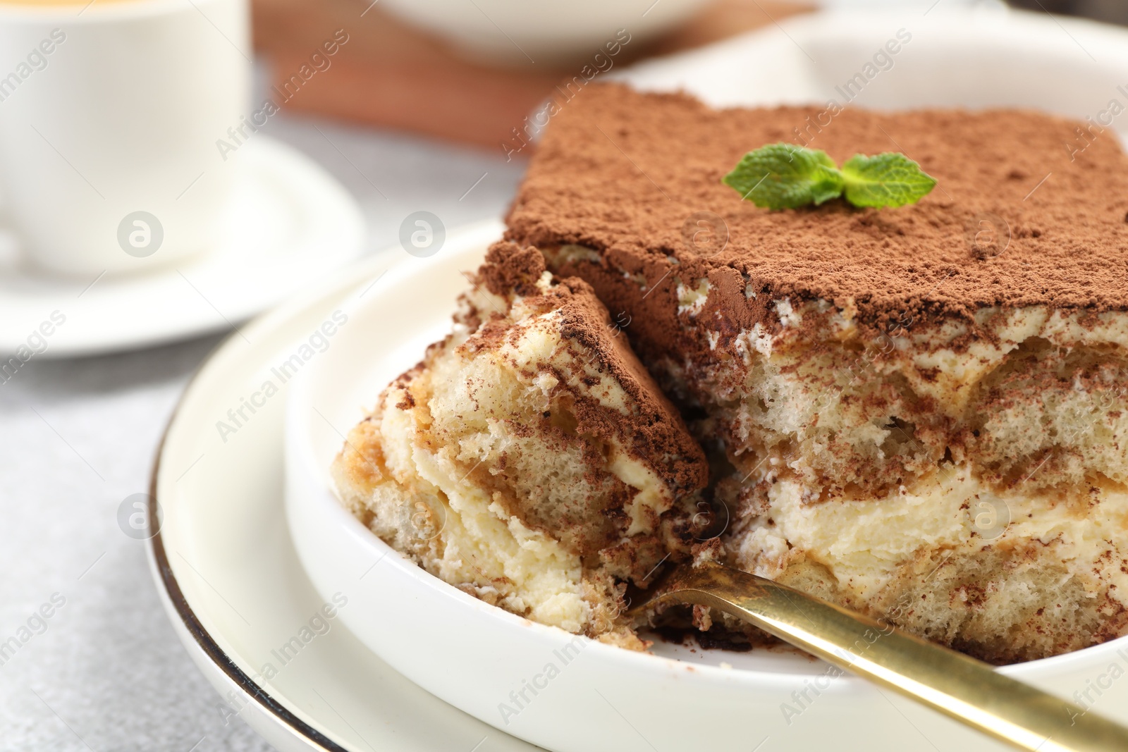 Photo of Delicious tiramisu with mint on light table, closeup