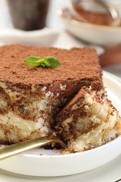 Photo of Delicious tiramisu with mint on plate, closeup