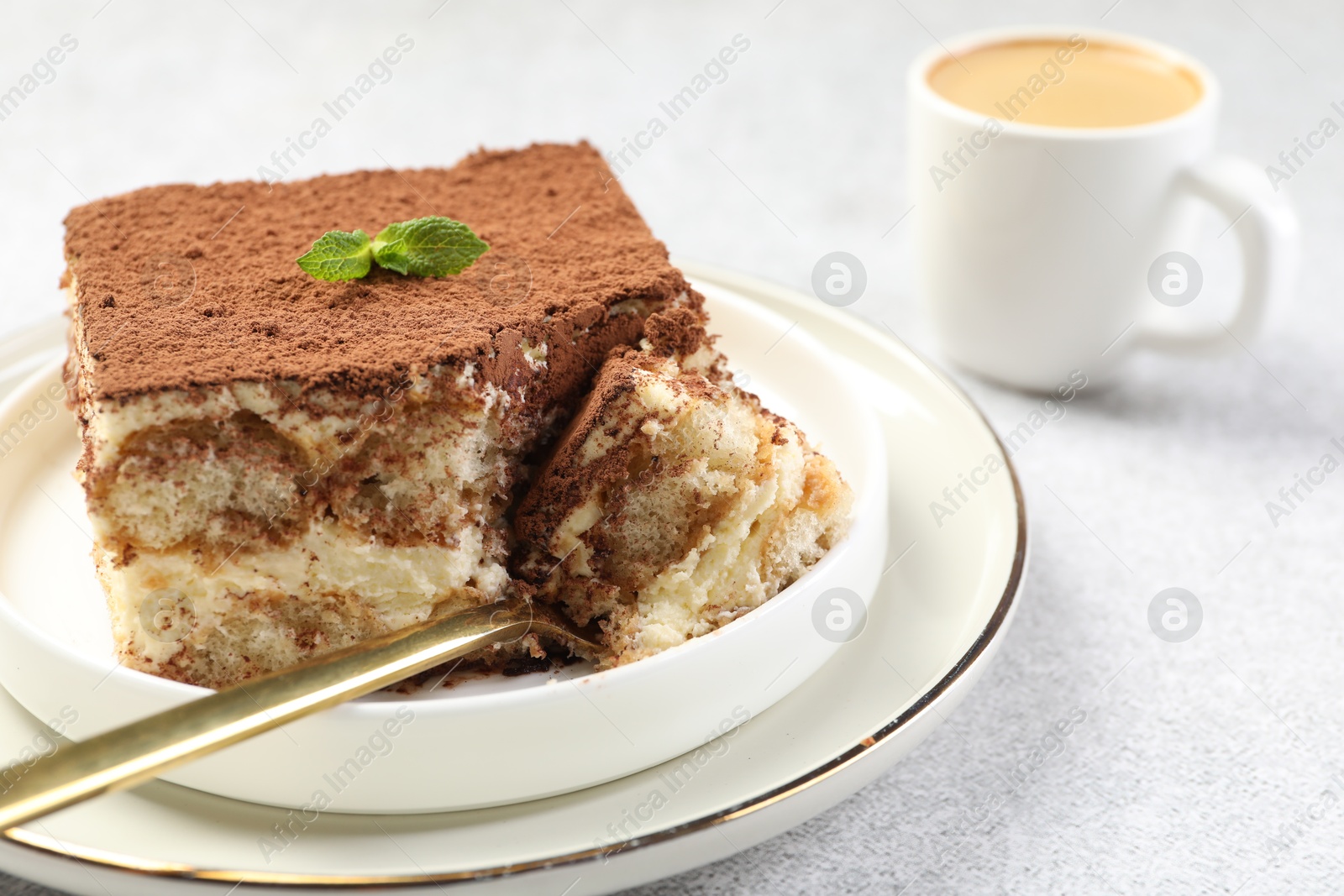 Photo of Delicious tiramisu with mint on light table, closeup