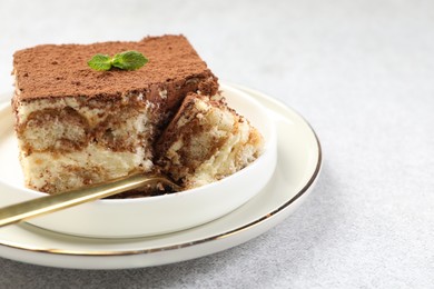 Photo of Delicious tiramisu with mint on light table, closeup