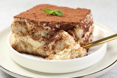 Photo of Delicious tiramisu with mint on light table, closeup