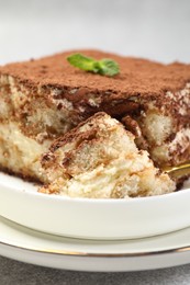 Photo of Delicious tiramisu with mint on grey table, closeup