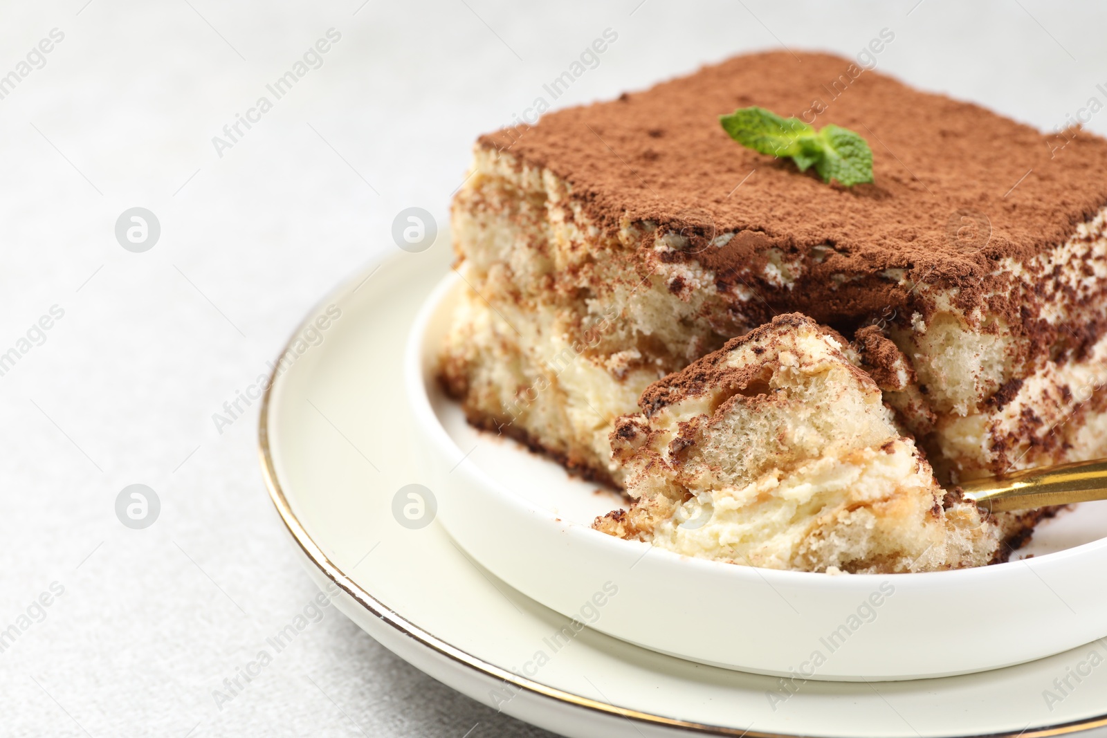 Photo of Delicious tiramisu with mint on light table, closeup