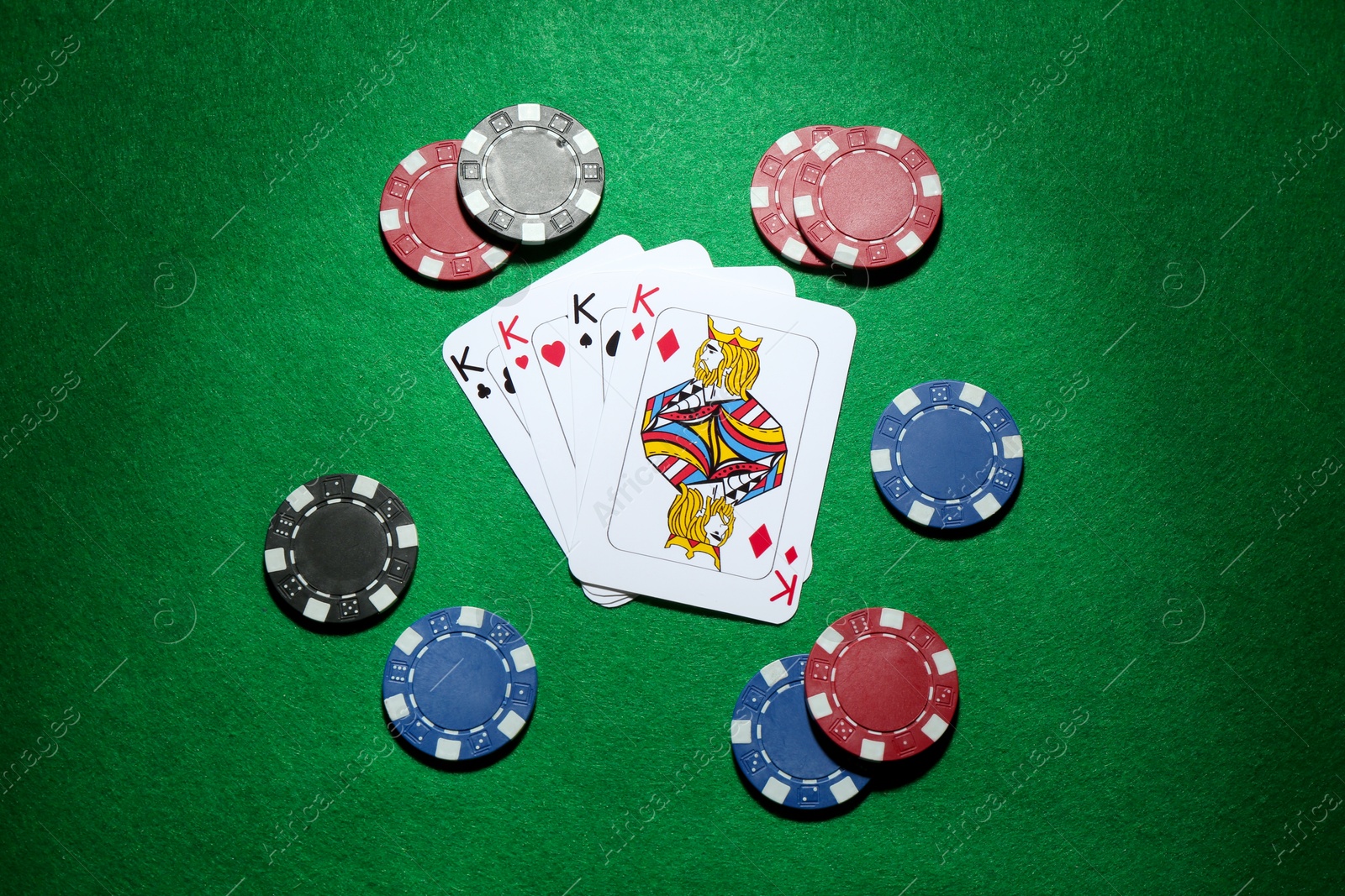 Photo of Poker chips and playing cards on green table, flat lay