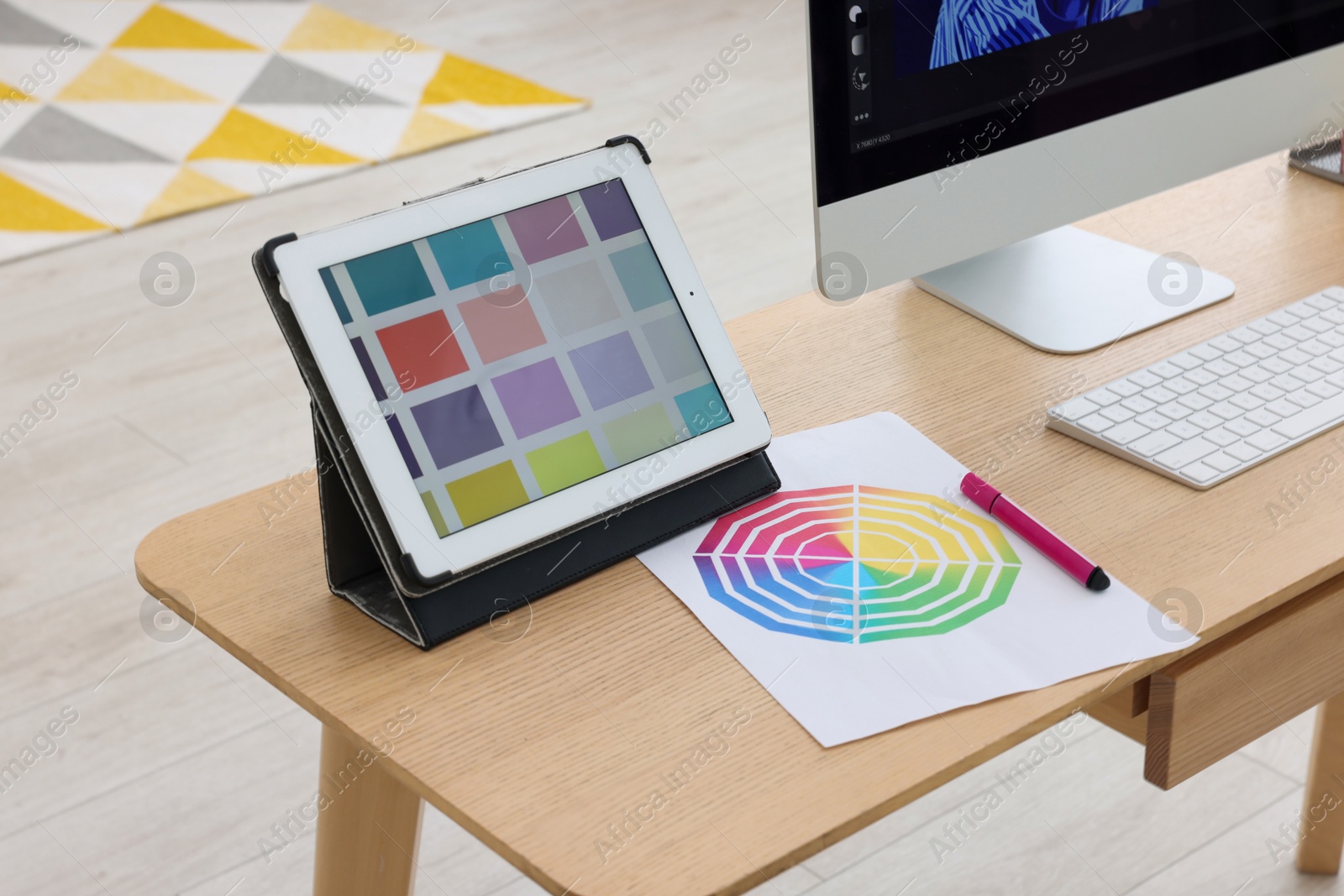 Photo of Designer's workplace with computer, tablet and color palette on wooden table indoors